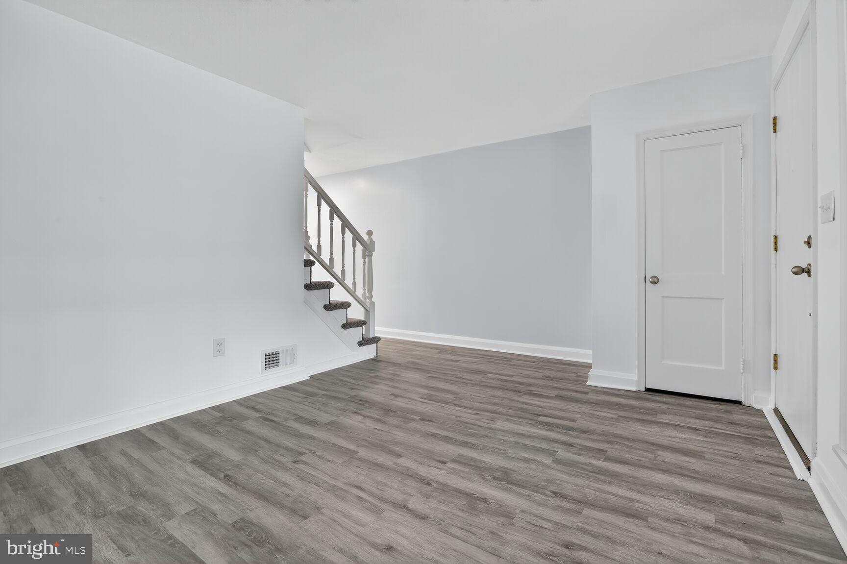 8258 Kavanagh Road Baltimore, MD 21222 - Photo 5 of 19 a view of an empty room with wooden floor and stairs