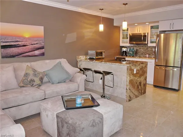 a living room with furniture and a refrigerator