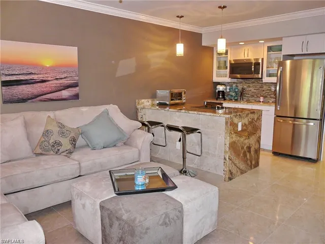 a living room with furniture and a refrigerator