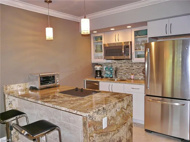 a kitchen with stainless steel appliances granite countertop a refrigerator a stove a sink and a microwave