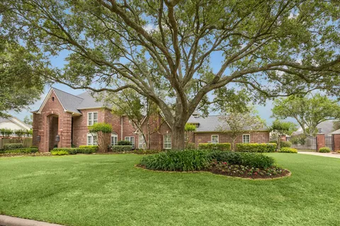 a front view of a house with a garden and trees