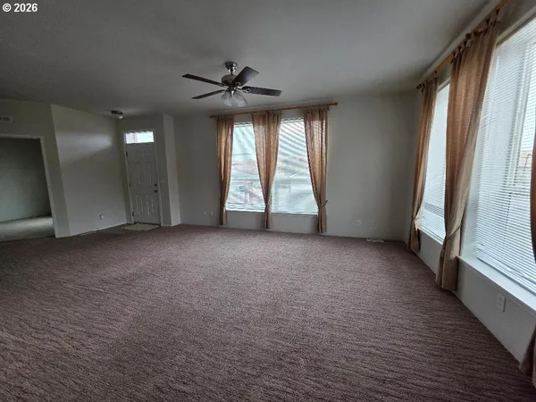 an empty room with windows and ceiling fan