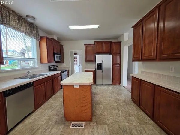 a kitchen with stainless steel appliances granite countertop a sink stove refrigerator and cabinets