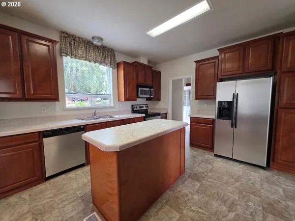 a kitchen with stainless steel appliances granite countertop a sink a stove and a wooden cabinets