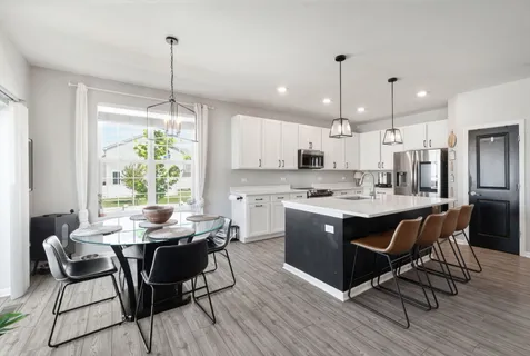 a kitchen with stainless steel appliances granite countertop a stove a refrigerator a sink dishwasher a dining table and chairs with wooden floor