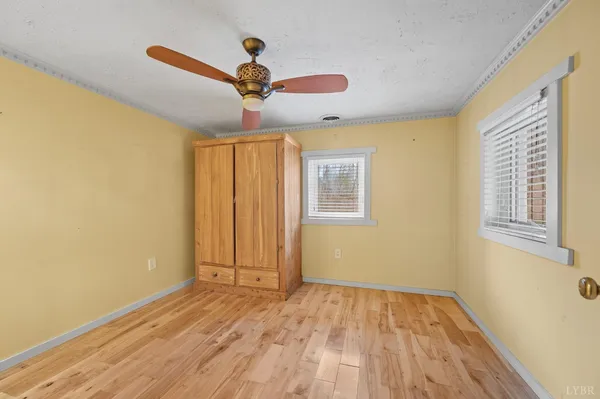 a view of empty room with wooden floor and fan