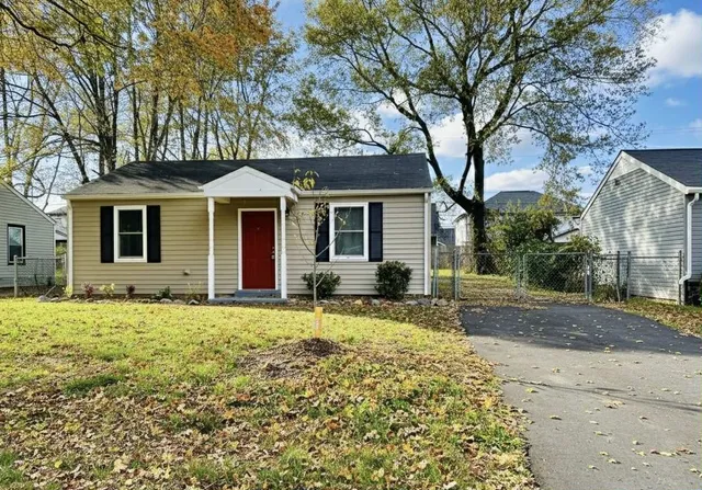 a front view of a house with a garden and tree
