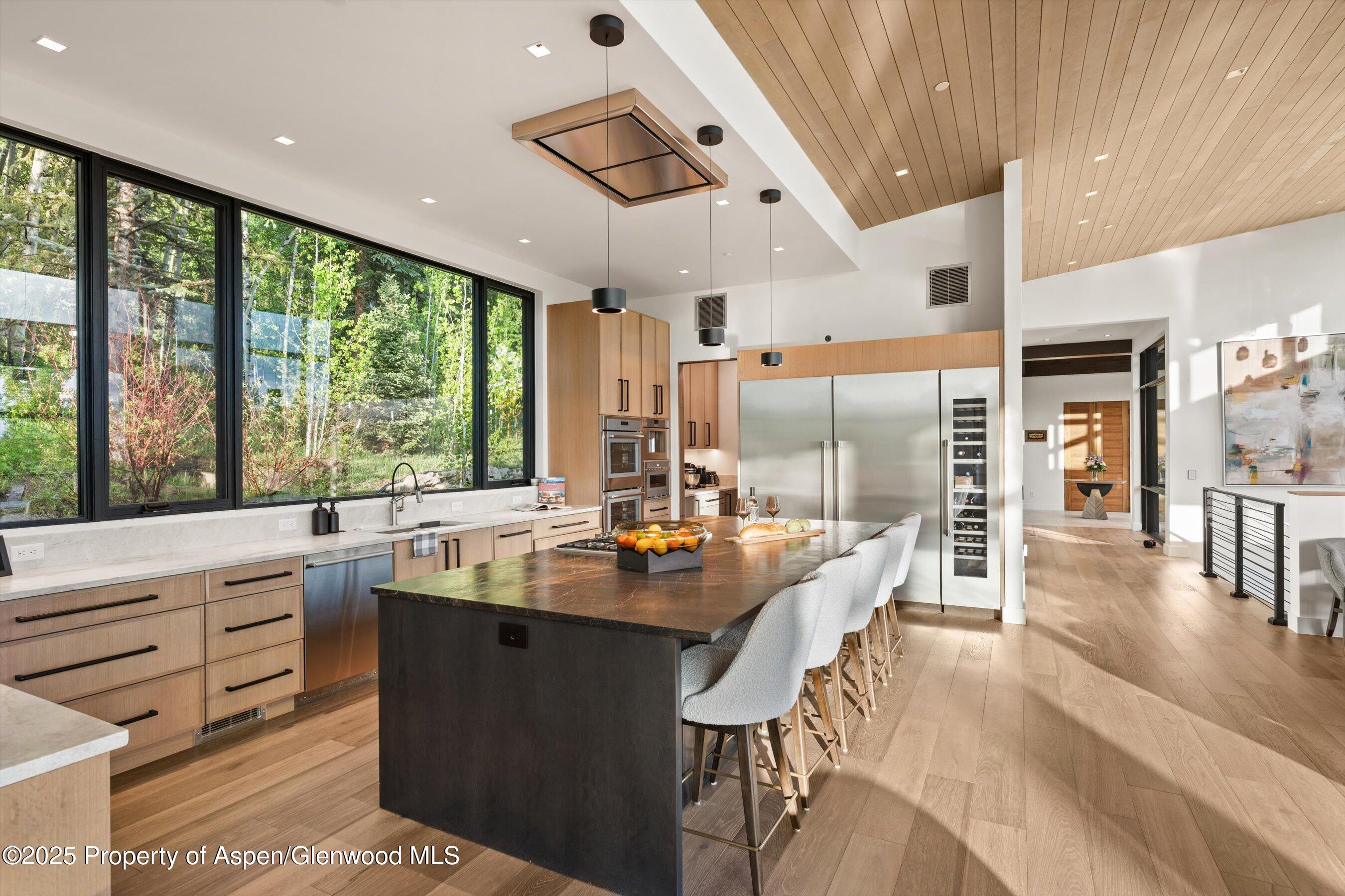 1234 Wood Road Snowmass Village, CO 81615 - Photo 15 of 66 a dining hall with stainless steel appliances kitchen island granite countertop a table chairs and a view of living room