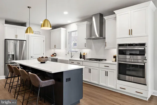 a kitchen with stainless steel appliances granite countertop a sink a stove a refrigerator and island with wooden floor