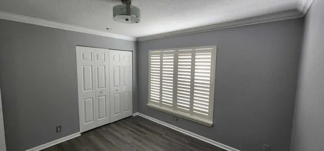 a view of an empty room with a window and wooden floor