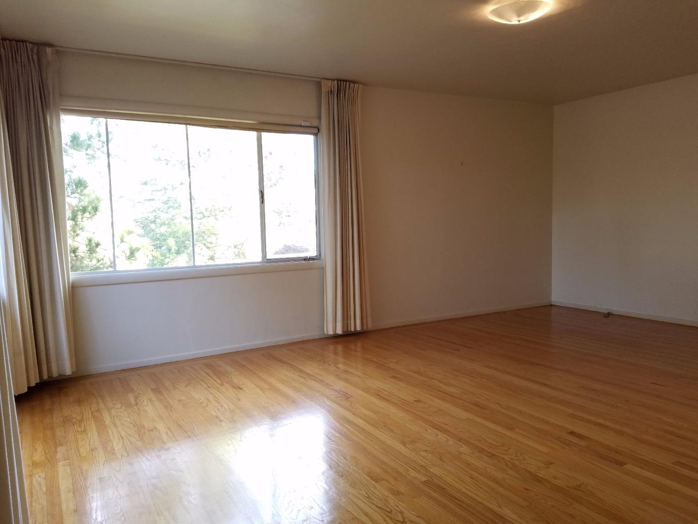 940 Black Mountain Road Hillsborough, CA 94010 - Photo 11 of 20 an empty room with wooden floor and windows
