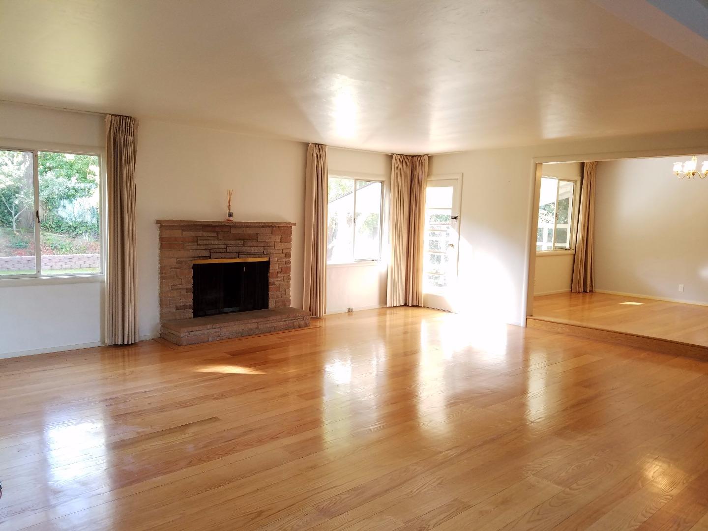 940 Black Mountain Road Hillsborough, CA 94010 - Photo 5 of 20 an empty room with wooden floor fireplace and windows