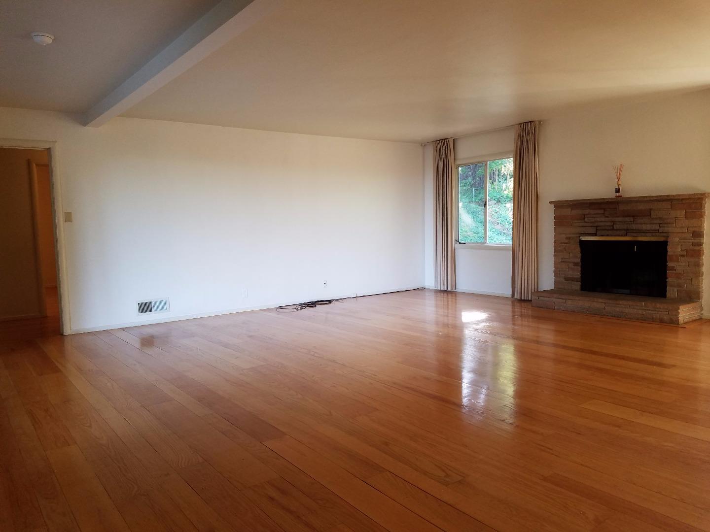 940 Black Mountain Road Hillsborough, CA 94010 - Photo 6 of 20 an empty room with wooden floor fireplace and windows