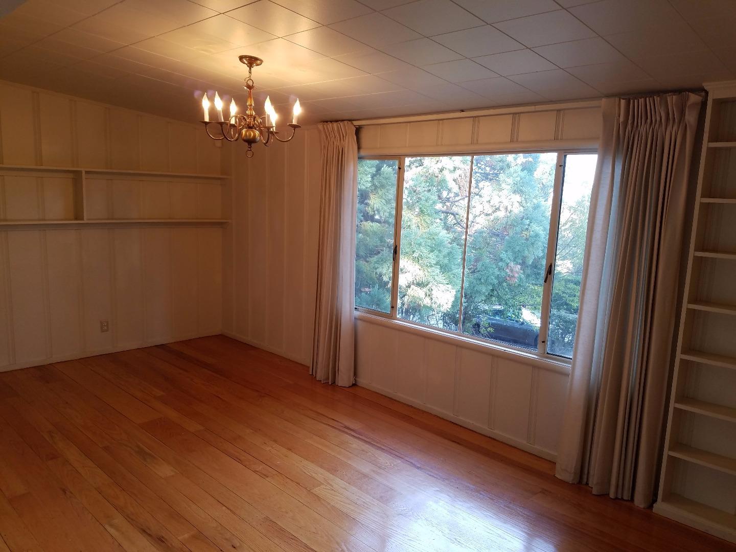 940 Black Mountain Road Hillsborough, CA 94010 - Photo 7 of 20 an empty room with wooden floor and windows