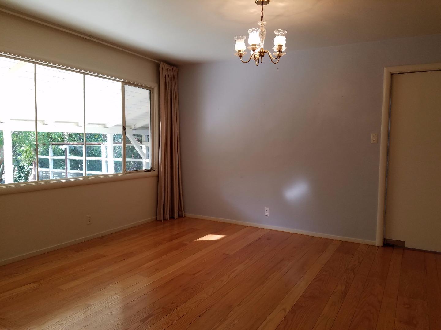 940 Black Mountain Road Hillsborough, CA 94010 - Photo 10 of 20 an empty room with wooden floor and windows