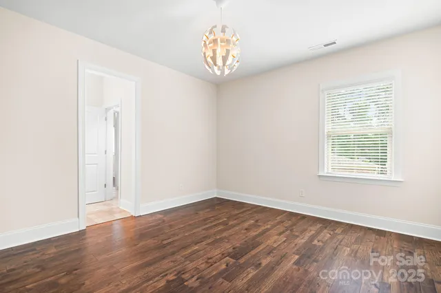 an empty room with wooden floor ceiling fan and windows