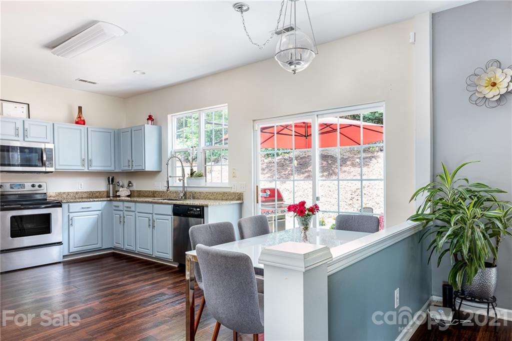 9239 Hillston Ridge Road Huntersville, NC 28078 - Photo 12 of 38 a kitchen with stainless steel appliances granite countertop a stove a sink dishwasher and a dining table with wooden floor