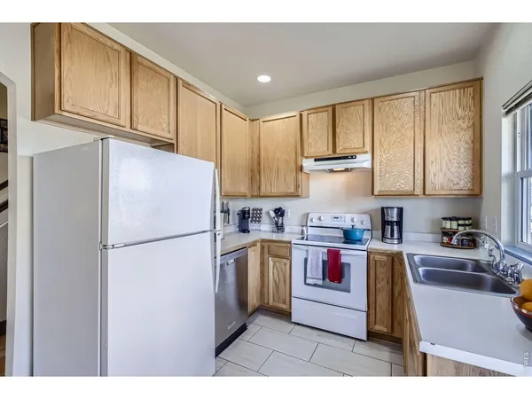 a kitchen with stainless steel appliances granite countertop a refrigerator sink stove and white cabinets