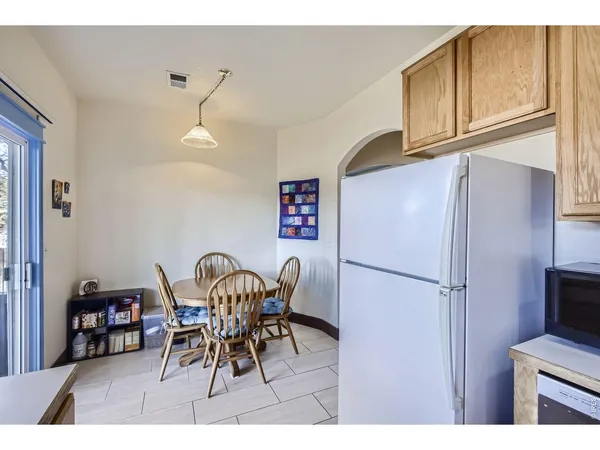 a kitchen with stainless steel appliances granite countertop a dining table chairs and a refrigerator