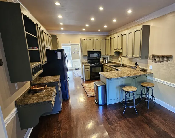 a kitchen with stainless steel appliances granite countertop a stove refrigerator and a dining table with wooden floor