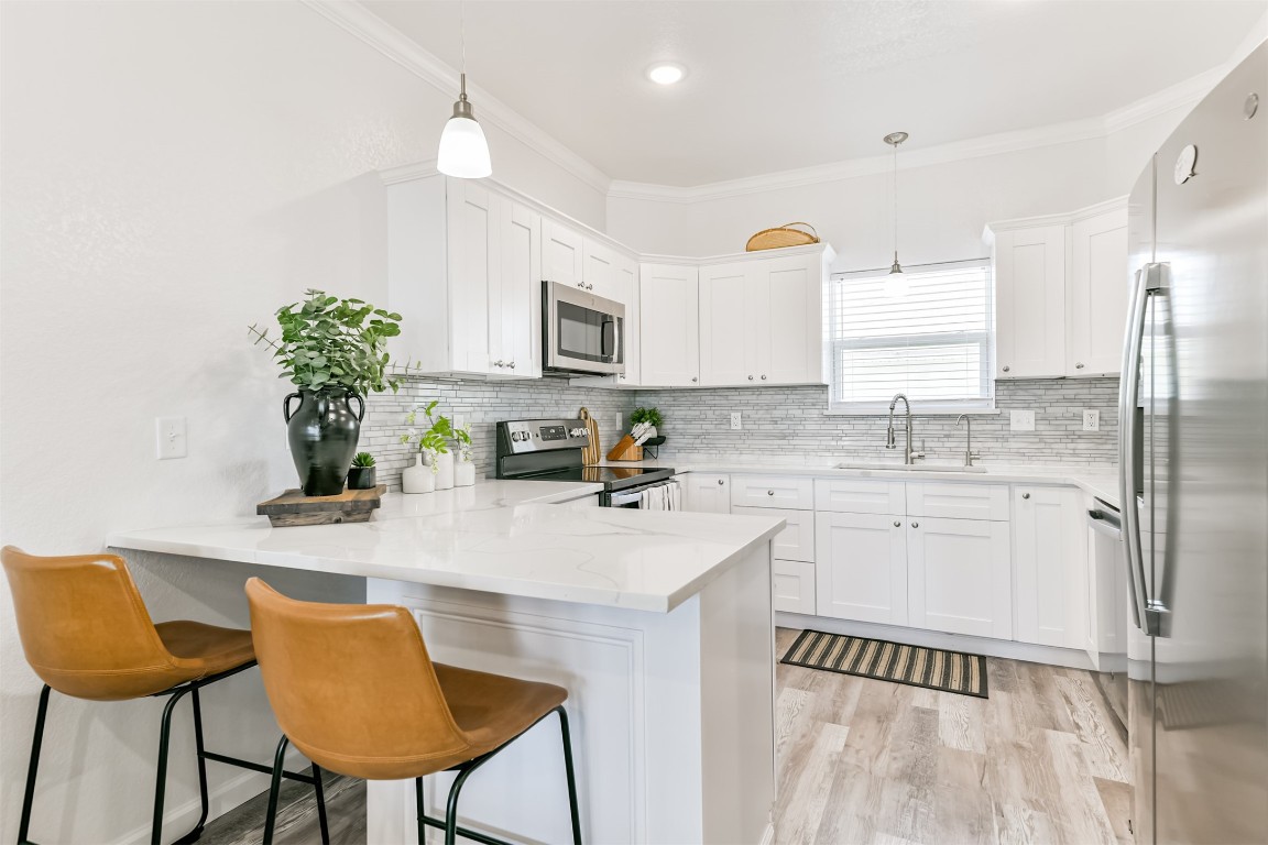 143 West Palm Surfside Beach, TX 77541 - Photo 13 of 38 a kitchen with stainless steel appliances granite countertop a refrigerator a sink dishwasher a stove a dining table and chairs with wooden floor
