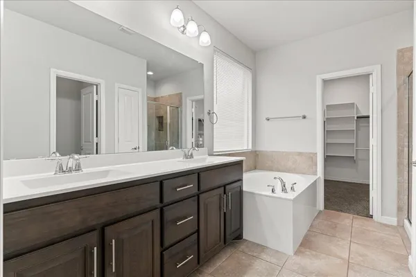 a spacious bathroom with a double vanity sink a mirror and a bathtub