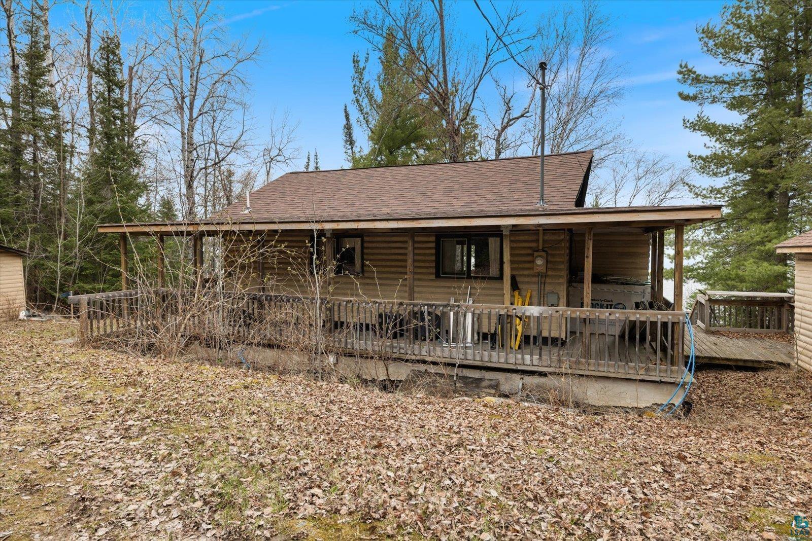 2014 West Frazer Bay Road Cook, MN 55723 - Photo 26 of 26 Log-sided residence featuring a brown shingle roof, a full-length covered porch, and a wood-slat deck with railing