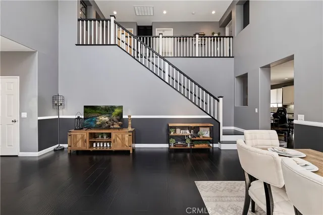 a living room with couches stairs and a dining table with wooden floor