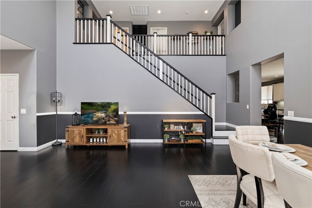 7029 Penny Court Rancho Cucamonga, CA 91739 - Photo 22 of 42 a living room with couches stairs and a dining table with wooden floor