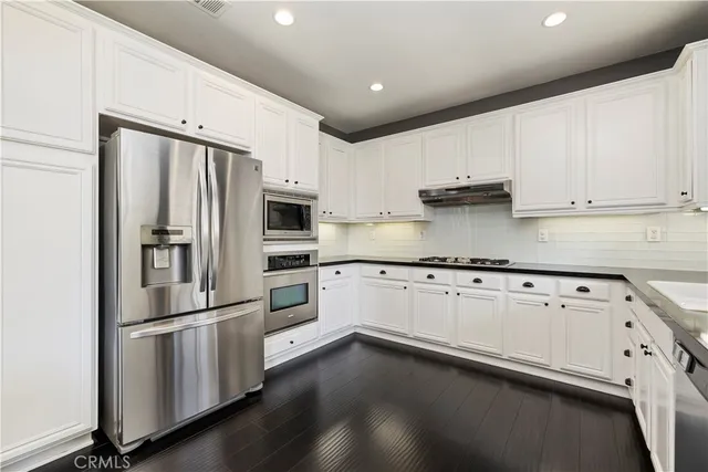 a kitchen with stainless steel appliances white cabinets and a refrigerator