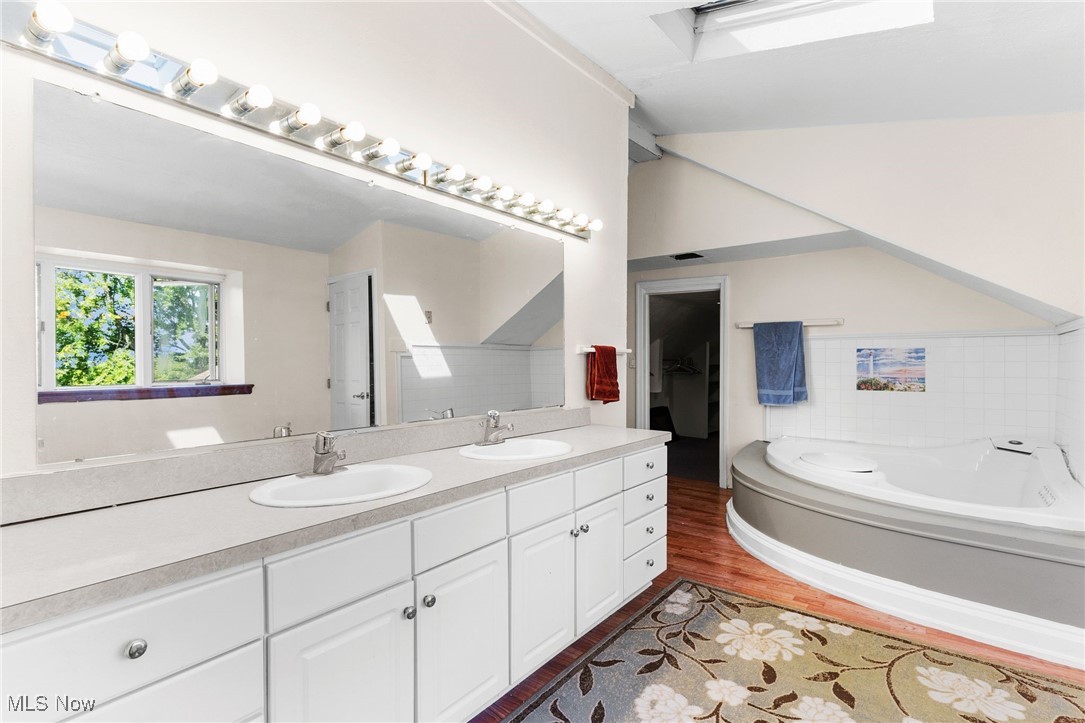 1963 Warner Road Southeast Hubbard, OH 44425 - Photo 37 of 46 Bathroom with wood-type flooring, dual bowl vanity, vaulted ceiling, and a tub to relax in