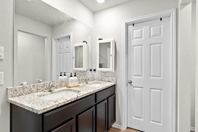 a bathroom with a granite countertop sink and a mirror