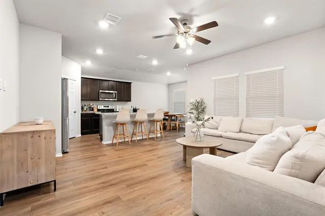 a living room with furniture kitchen view and a wooden floor