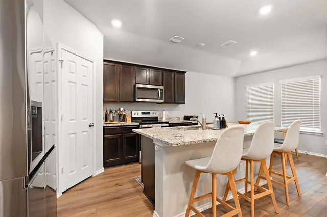 a kitchen with stainless steel appliances a stove a sink refrigerator and a refrigerator with wooden floor