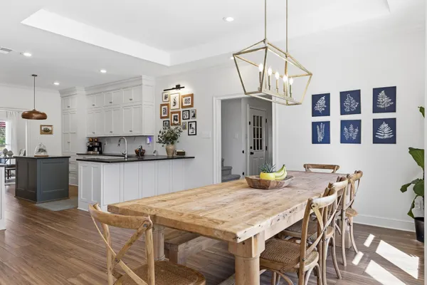 a kitchen with stainless steel appliances granite countertop a dining table chairs and white cabinets
