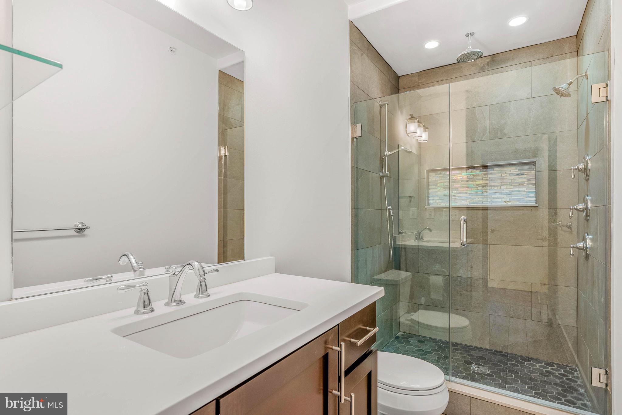 924 South 11th Street, Unit 101 Philadelphia, PA 19147 - Photo 15 of 27 a bathroom with a sink toilet a mirror and shower