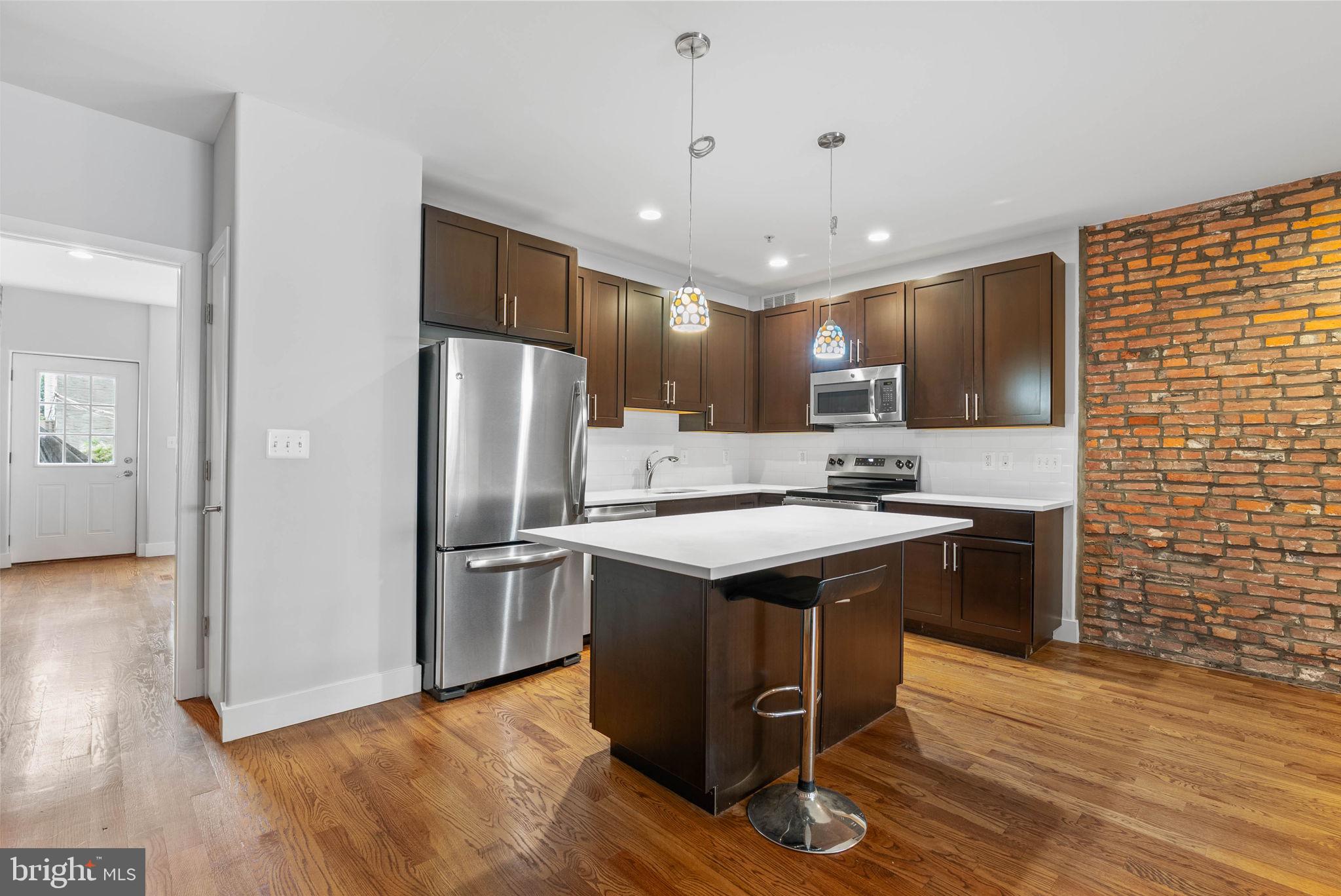 924 South 11th Street, Unit 101 Philadelphia, PA 19147 - Photo 10 of 27 a kitchen with stainless steel appliances granite countertop a sink a stove a refrigerator and island with wooden floor