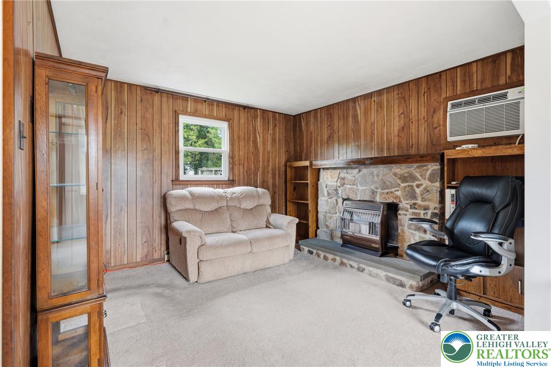 1385 Woodmere Road Pottstown, PA 19464 - Photo 8 of 57 A cozy living space features wood paneling and a stone fireplace, perfect for intimate gatherings.
