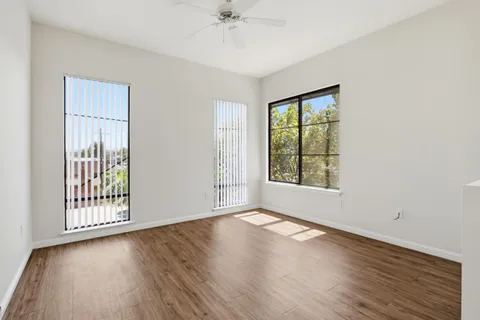 a view of an empty room with wooden floor and a window