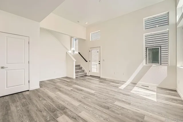 a view of an empty room with wooden floor and stairs