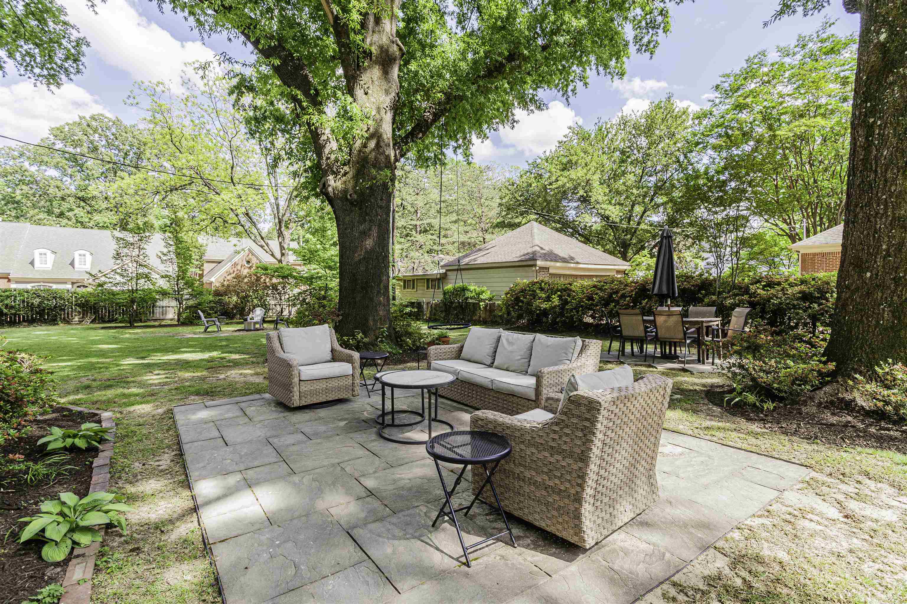 480 Colonial Road Memphis, TN 38117 - Photo 14 of 16 Expansive backyard featuring a stone patio, manicured lawn, and mature trees