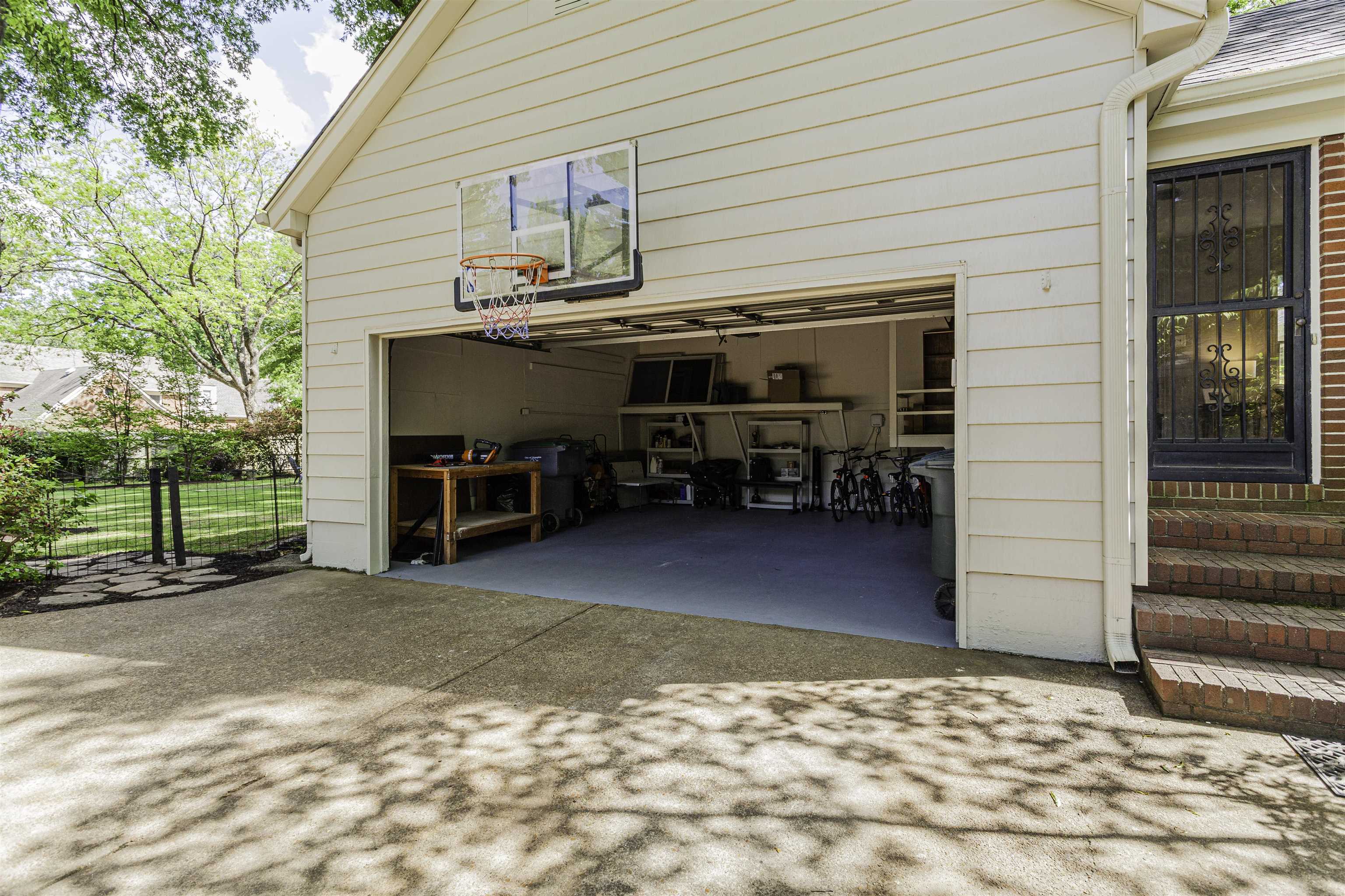480 Colonial Road Memphis, TN 38117 - Photo 16 of 16 Single-car garage with an open door, a concrete driveway, and an exterior brick staircase