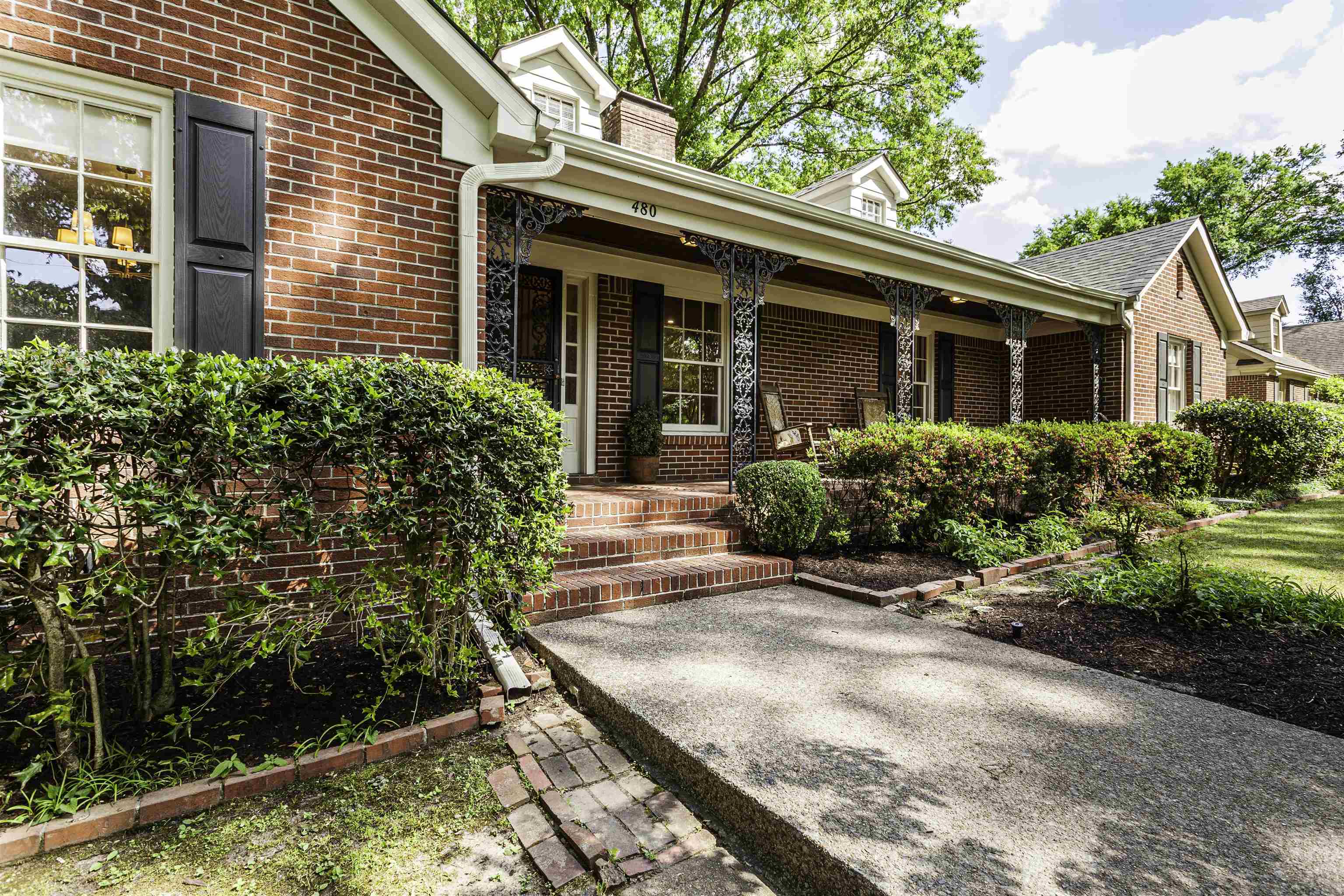 480 Colonial Road Memphis, TN 38117 - Photo 2 of 16 Brick exterior with black louvered shutters, covered front porch, decorative iron porch columns, brick steps, and established landscaping
