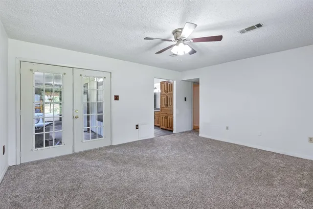 a view of an empty room with chandelier fan