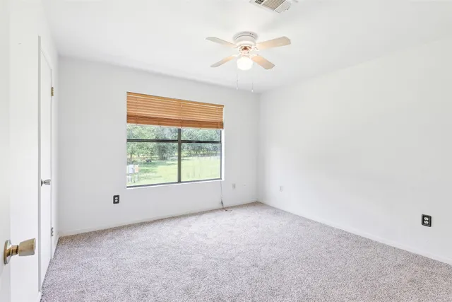 an empty room with a window and a fan