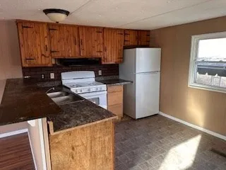 a kitchen with kitchen island a stove a refrigerator and a sink with wooden cabinets