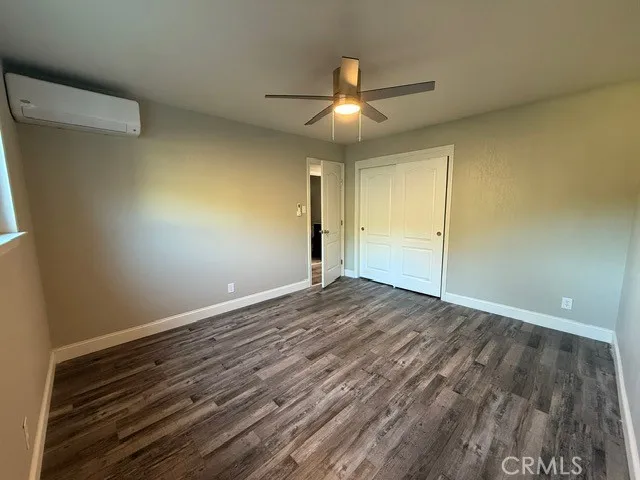 an empty room with wooden floor a ceiling fan and closet area