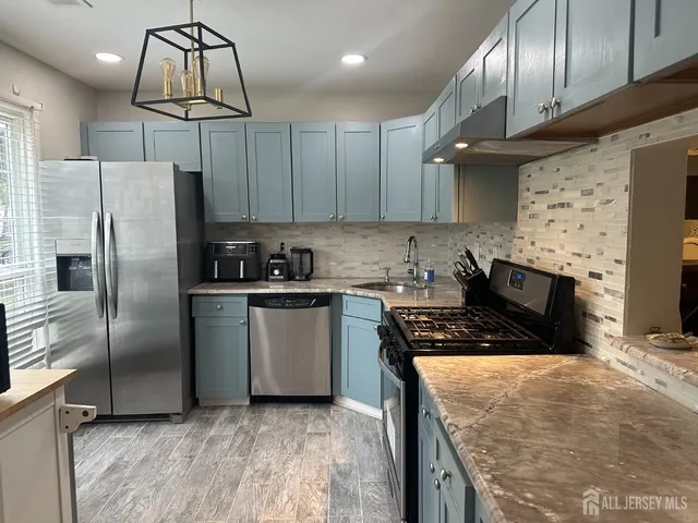 a kitchen with stainless steel appliances granite countertop a refrigerator a stove a sink and a microwave