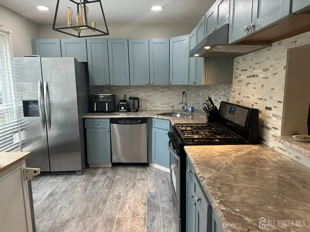 a kitchen with stainless steel appliances granite countertop a sink a stove a refrigerator and island