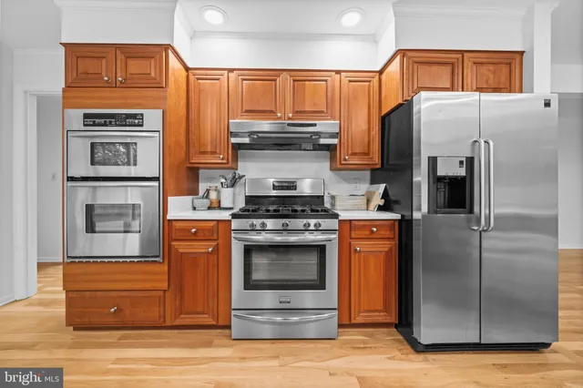 a kitchen with stainless steel appliances granite countertop wooden floors a stove a sink and a window